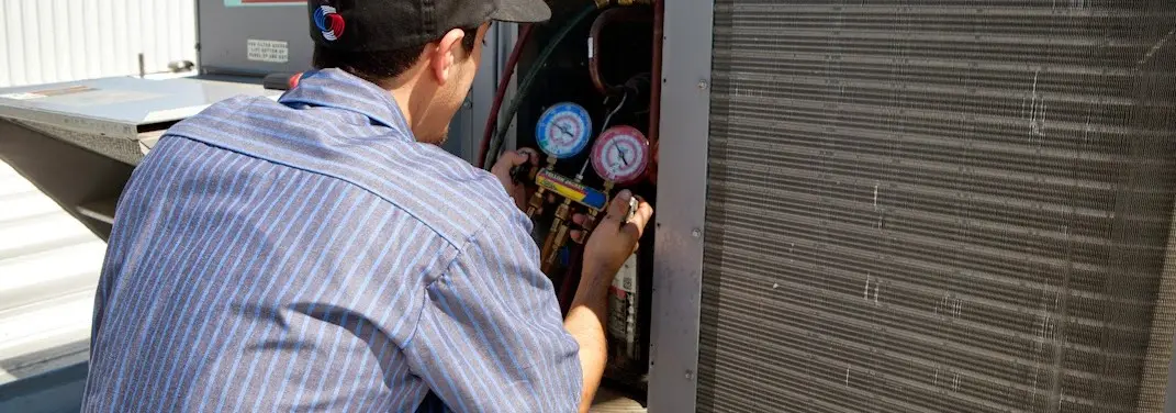 HVAC technician servicing a condenser unit in Algona