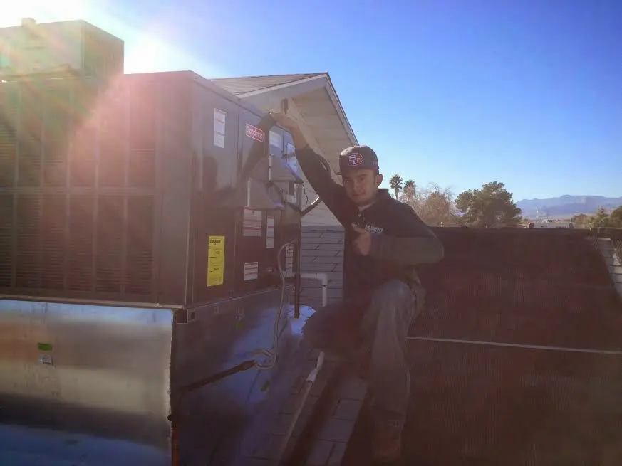 HVAC technician performing AC Tune-Up on a rooftop unit in Algona